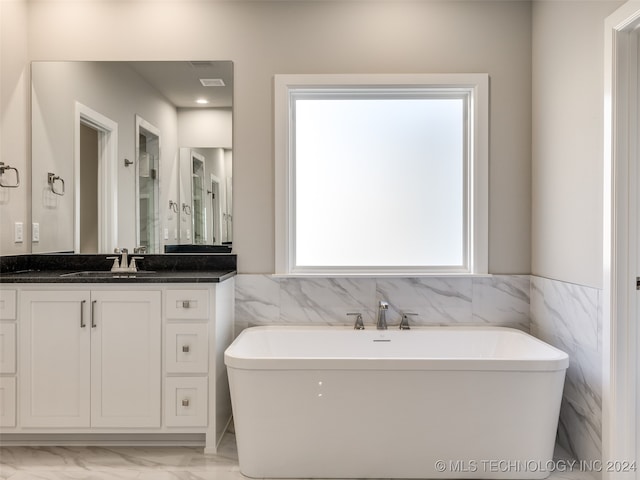 bathroom with a bathing tub, vanity, and tile walls