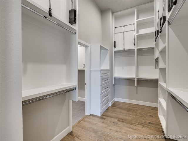 walk in closet with light hardwood / wood-style flooring