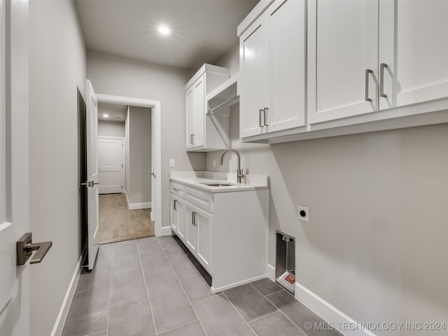 laundry area with sink, light tile patterned floors, cabinets, and hookup for an electric dryer