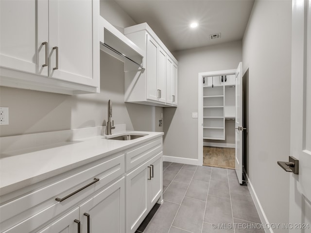 laundry room with cabinets, light tile patterned floors, and sink