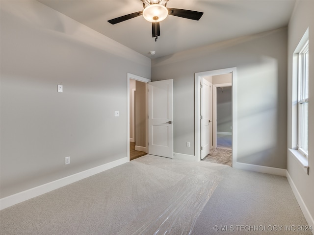 unfurnished bedroom with ceiling fan, light colored carpet, and a spacious closet