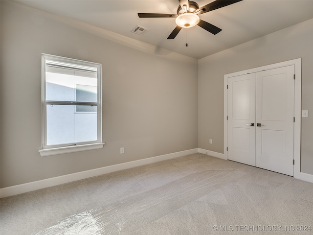 unfurnished bedroom featuring ceiling fan, a closet, and light colored carpet