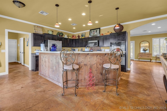 kitchen with pendant lighting, crown molding, a kitchen bar, a kitchen island, and appliances with stainless steel finishes