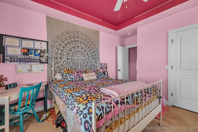 bedroom with carpet floors, ceiling fan, and a tray ceiling