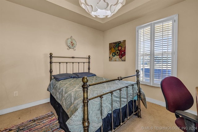 bedroom with a notable chandelier, carpet, and a tray ceiling