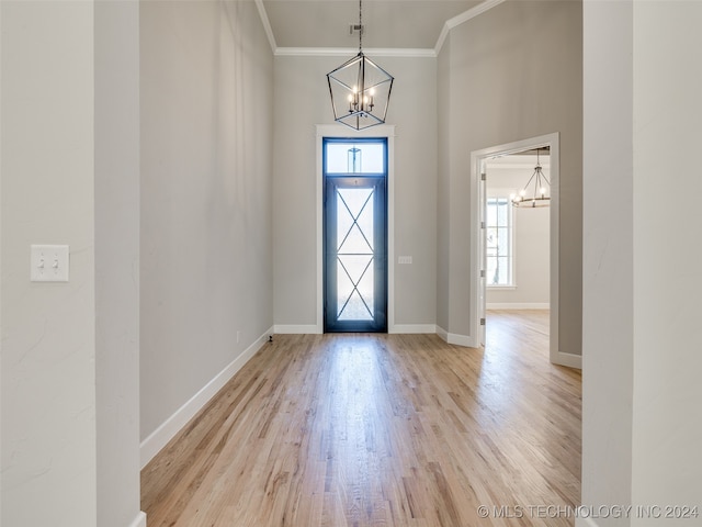 foyer entrance with a notable chandelier, light hardwood / wood-style floors, and ornamental molding