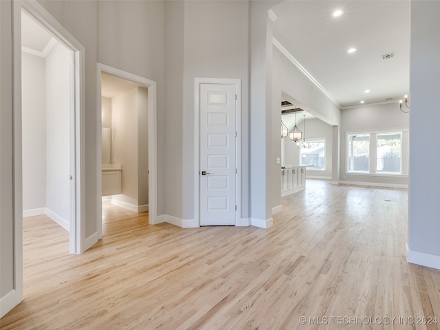 interior space with light hardwood / wood-style flooring, crown molding, and a notable chandelier