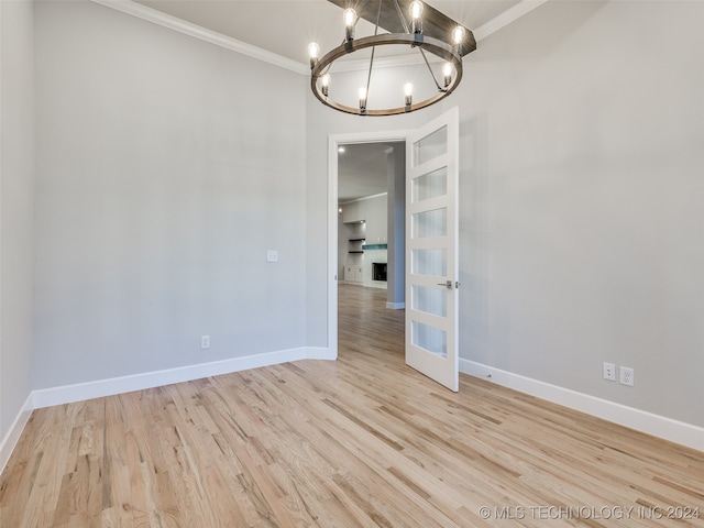 unfurnished dining area with a chandelier, ornamental molding, and light hardwood / wood-style flooring