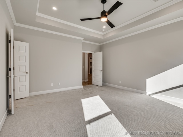 carpeted spare room with ceiling fan, a raised ceiling, and crown molding