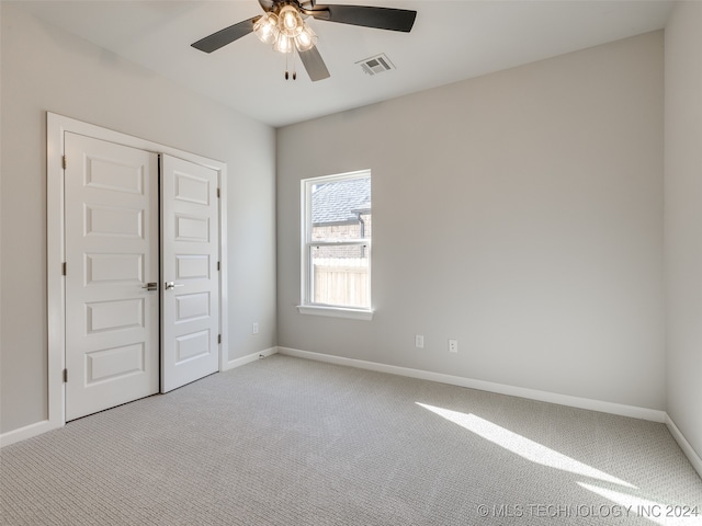 unfurnished bedroom featuring ceiling fan, light carpet, and a closet