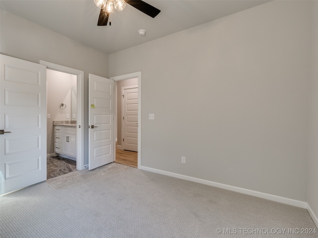 unfurnished bedroom featuring light carpet, connected bathroom, and ceiling fan