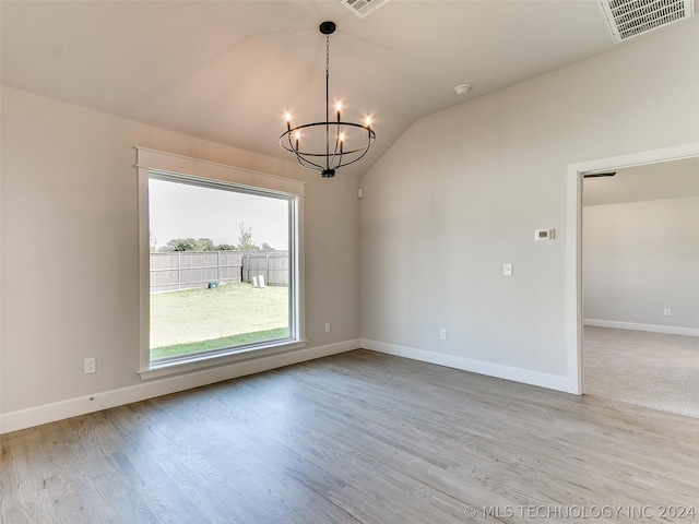 carpeted spare room featuring an inviting chandelier and vaulted ceiling