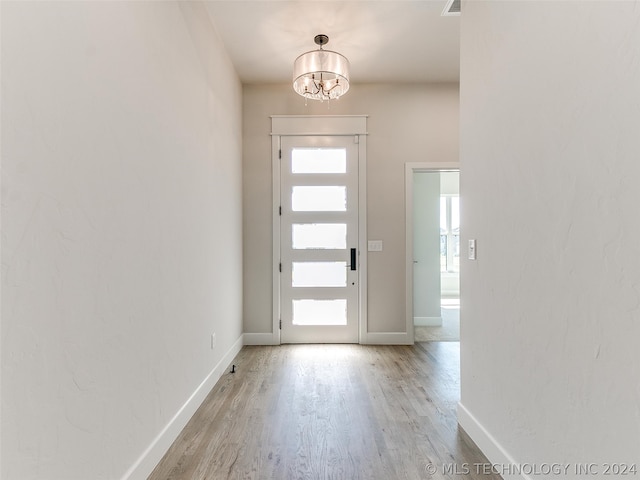 entryway featuring a healthy amount of sunlight, light hardwood / wood-style flooring, and a chandelier