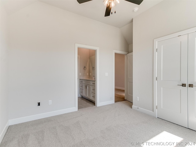 unfurnished bedroom with light carpet, vaulted ceiling, a closet, and ensuite bathroom