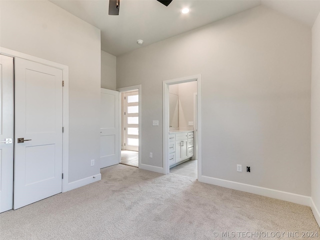 unfurnished bedroom with light colored carpet, lofted ceiling, and ensuite bath