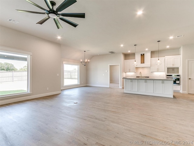 unfurnished living room with sink, ceiling fan with notable chandelier, and light hardwood / wood-style flooring