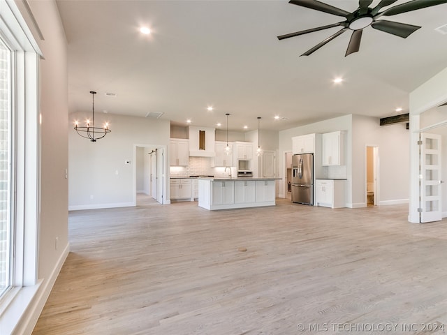 unfurnished living room featuring sink, ceiling fan with notable chandelier, and light hardwood / wood-style floors