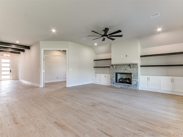 unfurnished living room featuring beam ceiling, a stone fireplace, light hardwood / wood-style flooring, and ceiling fan