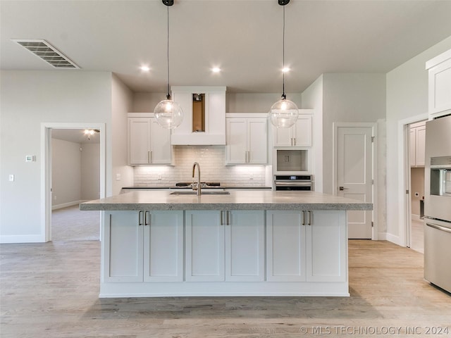 kitchen featuring a kitchen island with sink, white cabinetry, and stainless steel appliances