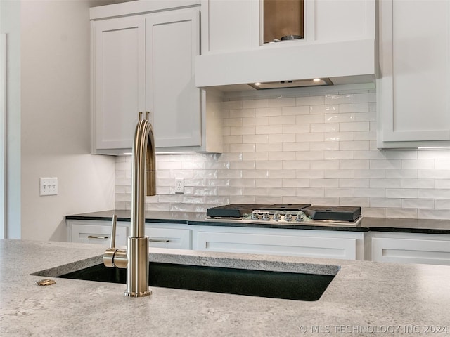 kitchen with white cabinetry, light stone counters, and backsplash