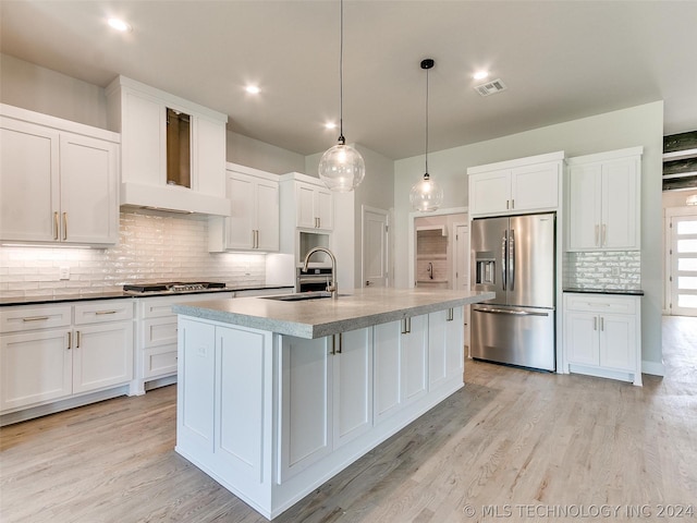 kitchen featuring pendant lighting, sink, appliances with stainless steel finishes, custom range hood, and a center island with sink