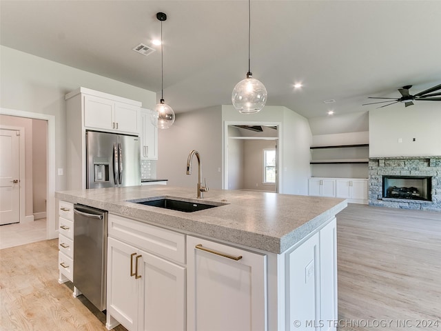 kitchen featuring sink, a fireplace, light wood-type flooring, and stainless steel appliances