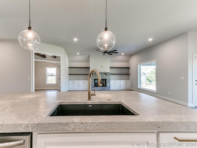 kitchen featuring plenty of natural light, sink, light stone counters, and a fireplace