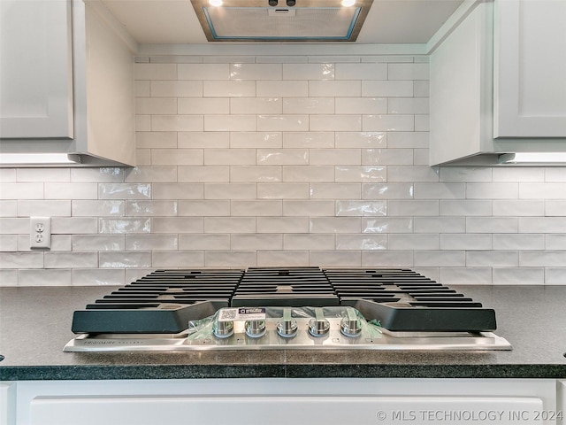 interior details featuring stainless steel gas stovetop, white cabinetry, tasteful backsplash, and extractor fan