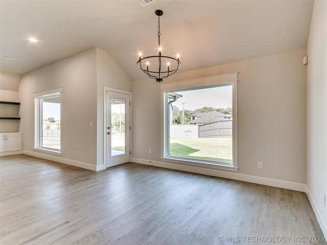 interior space featuring vaulted ceiling, a healthy amount of sunlight, an inviting chandelier, and light wood-type flooring