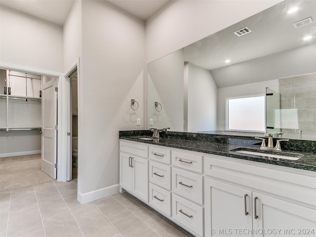 bathroom with tile patterned flooring, dual vanity, vaulted ceiling, and toilet