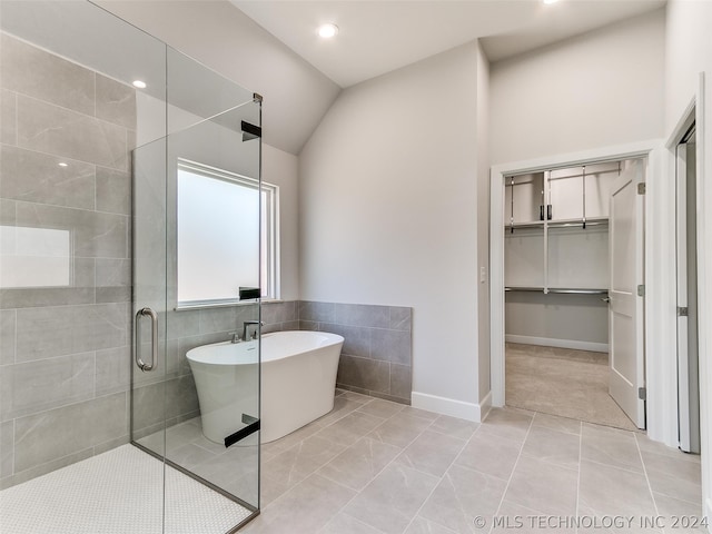 bathroom featuring tile patterned floors, independent shower and bath, vaulted ceiling, and tile walls