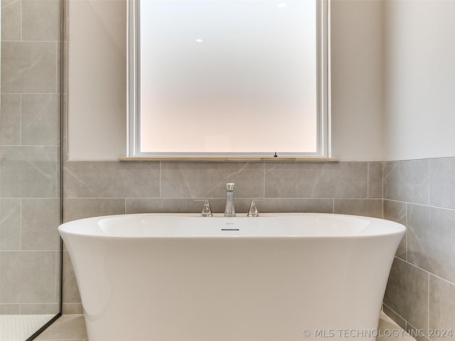 bathroom with tile walls and a tub to relax in