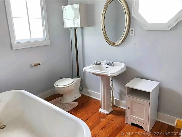 bathroom featuring hardwood / wood-style flooring, toilet, and a bathtub