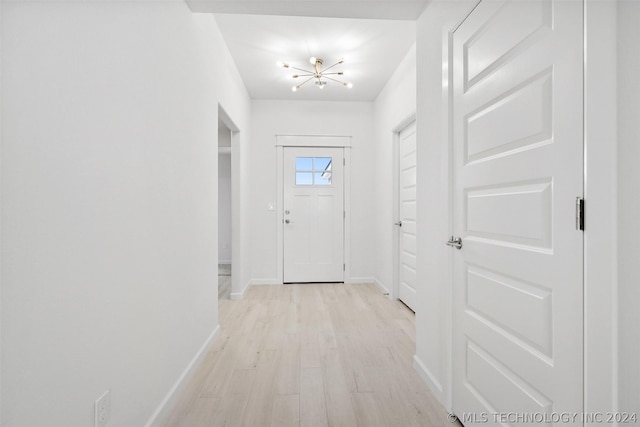 doorway with light wood-type flooring and an inviting chandelier