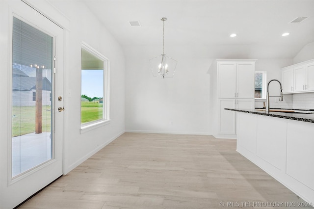 unfurnished dining area featuring sink, a notable chandelier, and light wood-type flooring