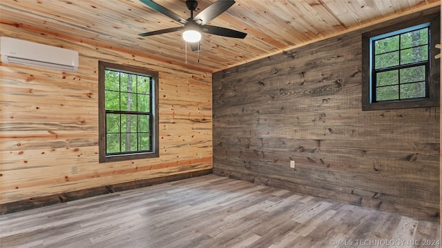 empty room featuring hardwood / wood-style flooring, wood walls, a wealth of natural light, and a wall mounted AC