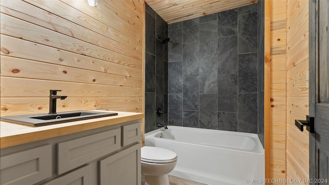 full bathroom with tiled shower / bath combo, wood walls, toilet, and vanity