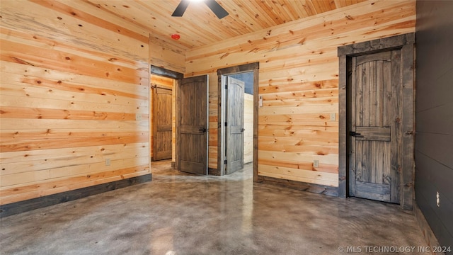 unfurnished room with concrete flooring, ceiling fan, wood ceiling, and wood walls