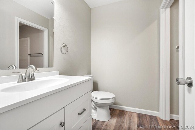 bathroom with hardwood / wood-style floors, vanity, and toilet