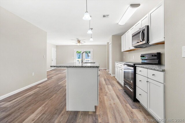 kitchen with white cabinetry, black electric range oven, a kitchen island with sink, and light hardwood / wood-style flooring