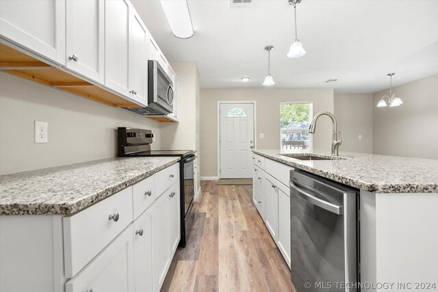 kitchen featuring appliances with stainless steel finishes, a kitchen island with sink, sink, decorative light fixtures, and light hardwood / wood-style flooring