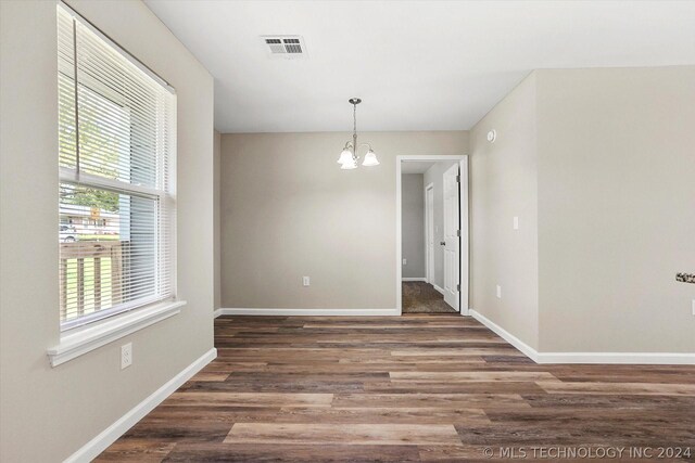 unfurnished dining area featuring dark hardwood / wood-style flooring and an inviting chandelier