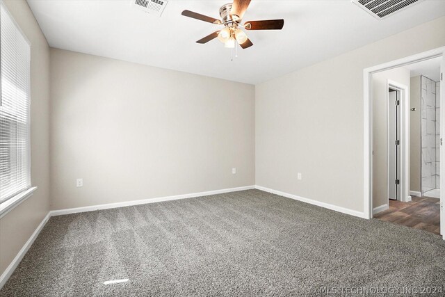 empty room with dark colored carpet and ceiling fan