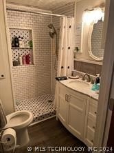 bathroom featuring curtained shower, hardwood / wood-style floors, oversized vanity, and toilet