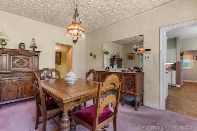 carpeted dining area with a chandelier and a textured ceiling