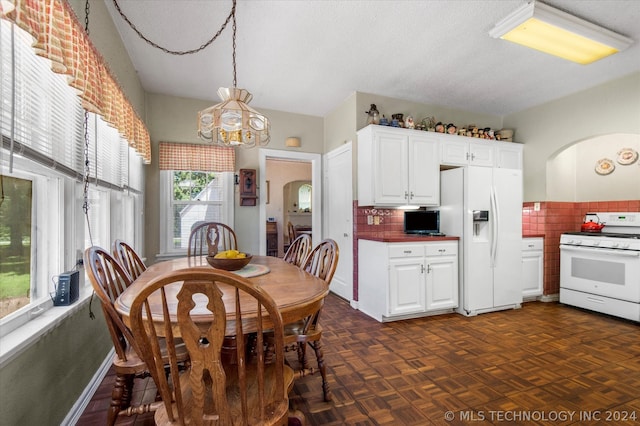 dining area with dark parquet floors, a textured ceiling, and an inviting chandelier