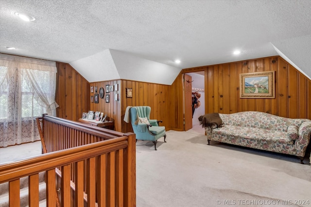 sitting room featuring wood walls, light carpet, a textured ceiling, and vaulted ceiling