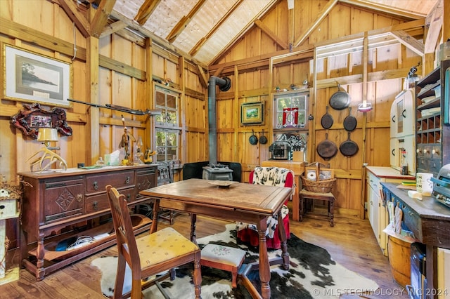 office featuring wooden walls, high vaulted ceiling, hardwood / wood-style floors, and a wood stove