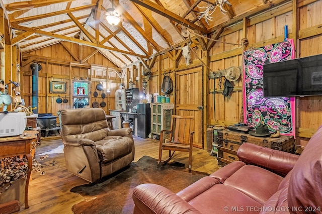 living room featuring wooden walls, beam ceiling, hardwood / wood-style flooring, and a wood stove