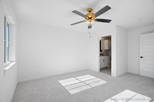 unfurnished bedroom featuring light carpet, ensuite bath, and ceiling fan